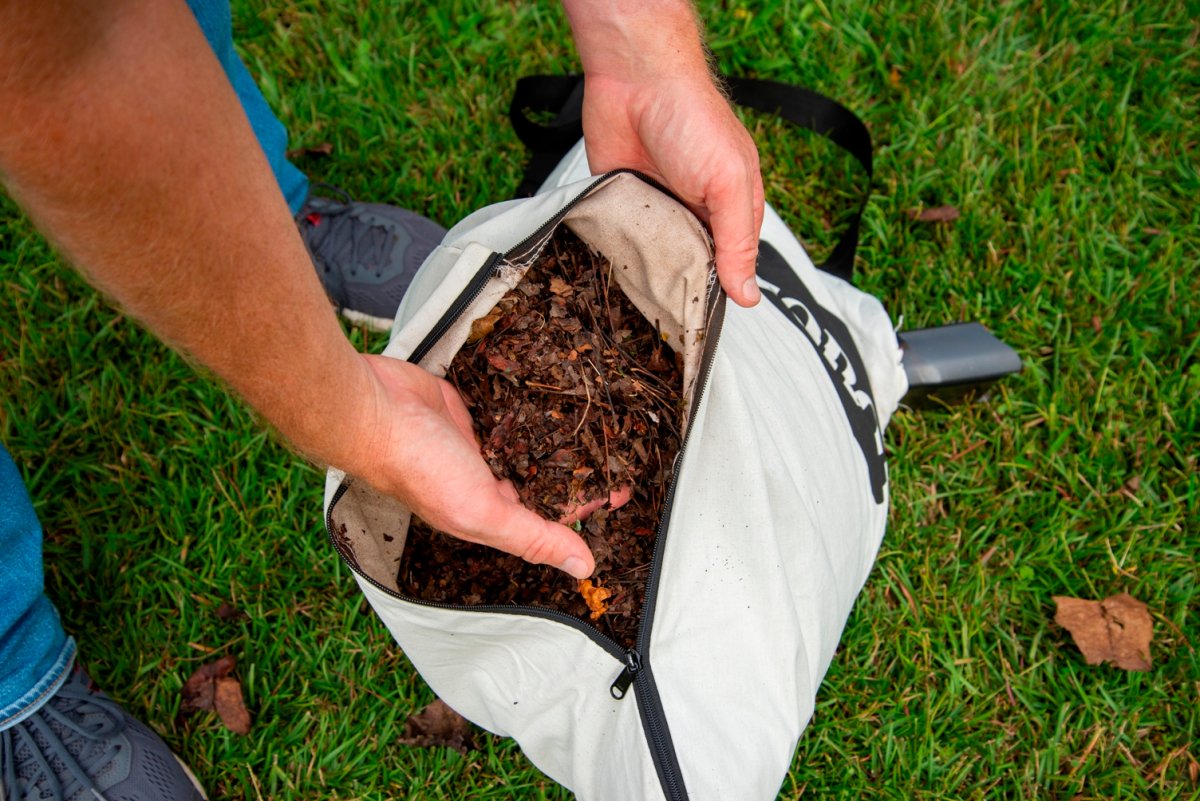 A person reaching into a bag full of mulched leaves created by the best leaf vacuum option