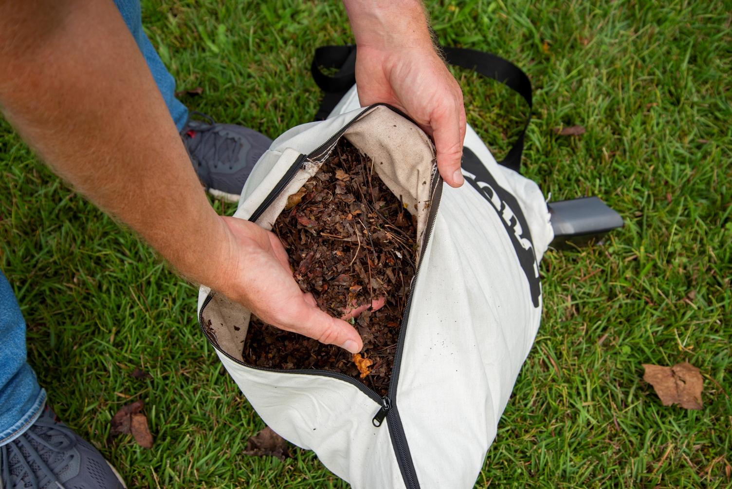 A person reaching into a bag full of mulched leaves created by the best leaf vacuum option