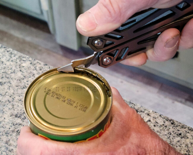 A person opening a can with a multitool