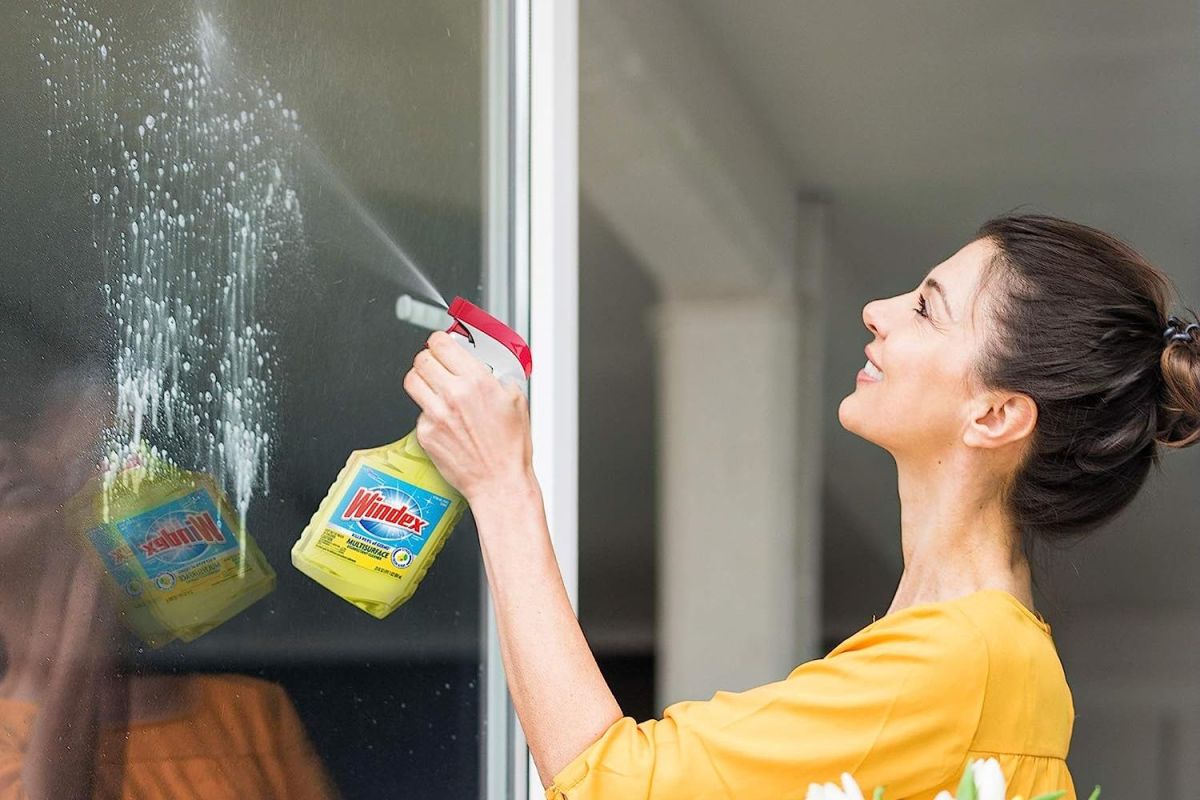 A person using the best disinfectant spray to clean a window