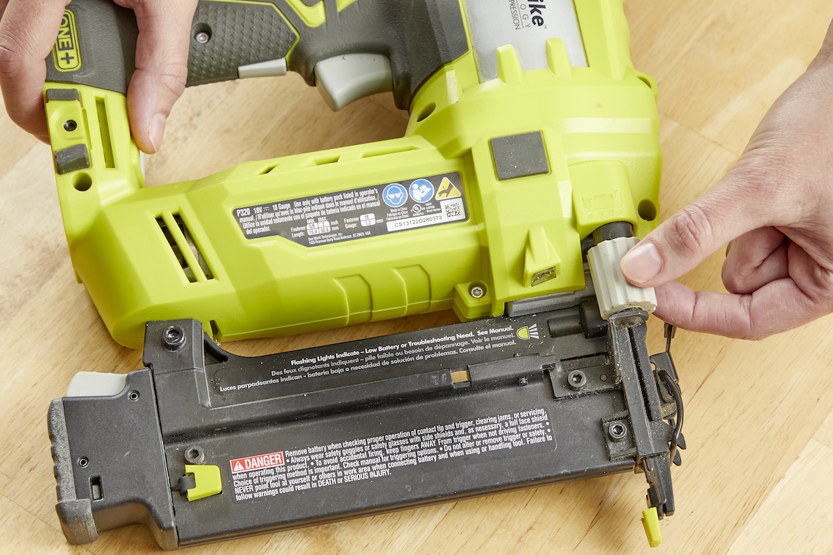 Person adjusts the depth adjustment dial on a Ryobi nail gun.