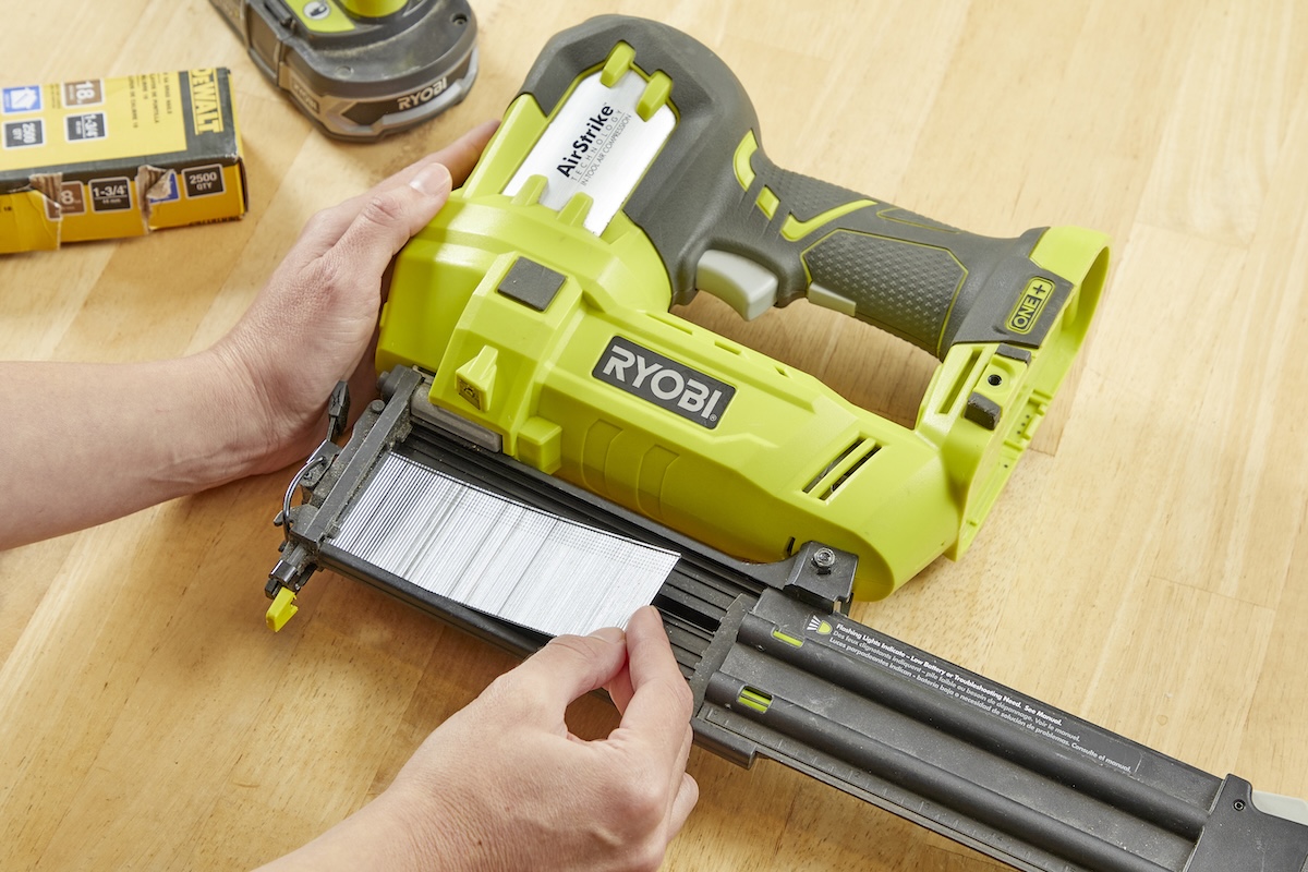 Person loads a row of nails into a Ryobi nail gun.