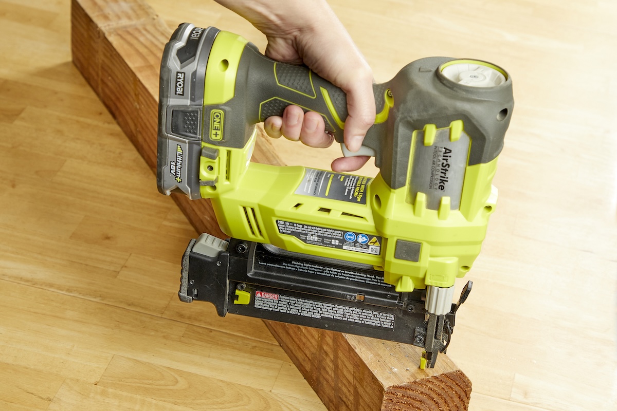 Person tests a nail gun on a piece of natural lumber.