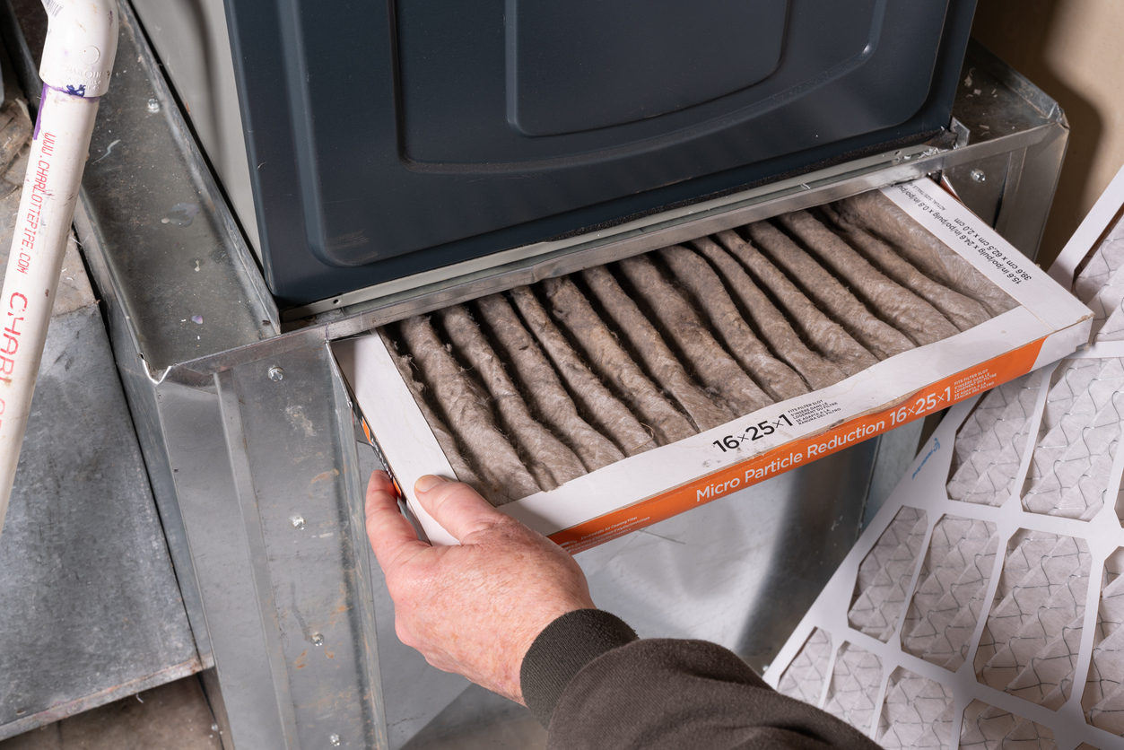 Replacing dirty furnace filter in home by man
