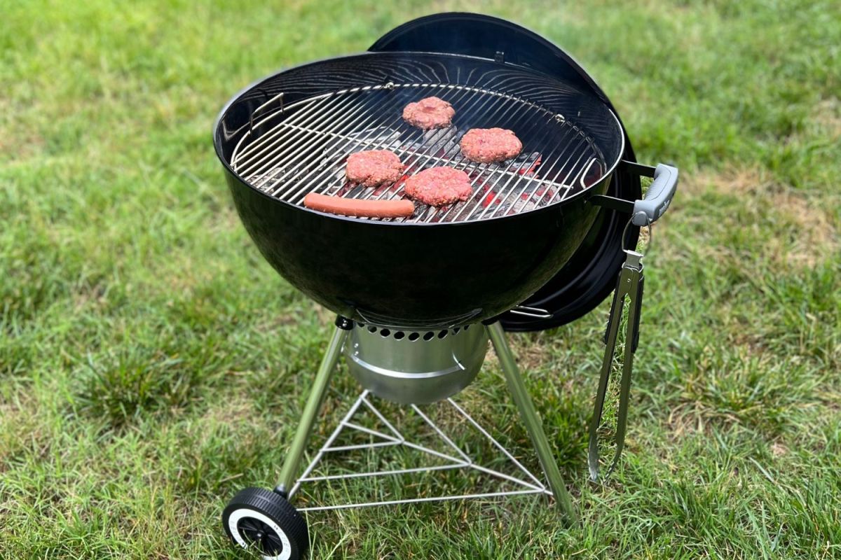 Four hamburgers and one hot dog on Weber charcoal kettle grill
