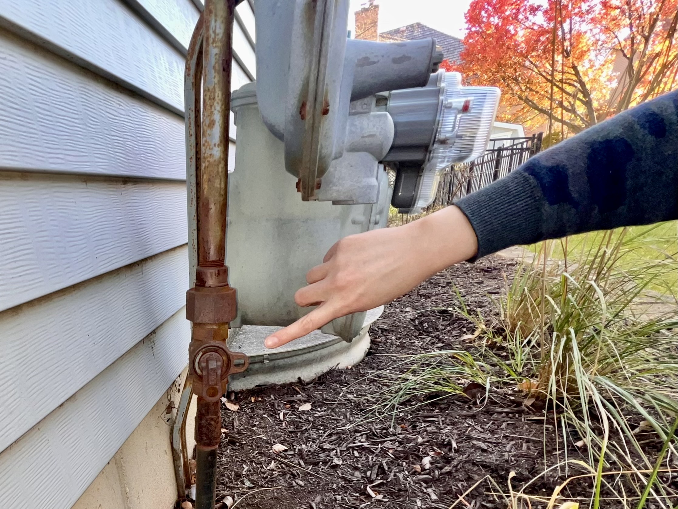 Woman pointing to shut off valve on home's exterior gas line.