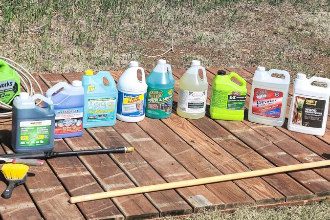 7 different bottles of deck cleaner lined up on a wooden deck