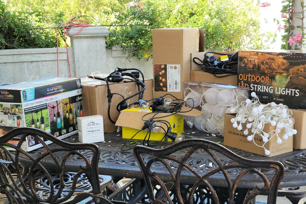 A group of the best outdoor string lights options and their packaging grouped together on an outdoor table