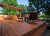 A spacious outdoor deck stained a cedar color with patio furniture on top.