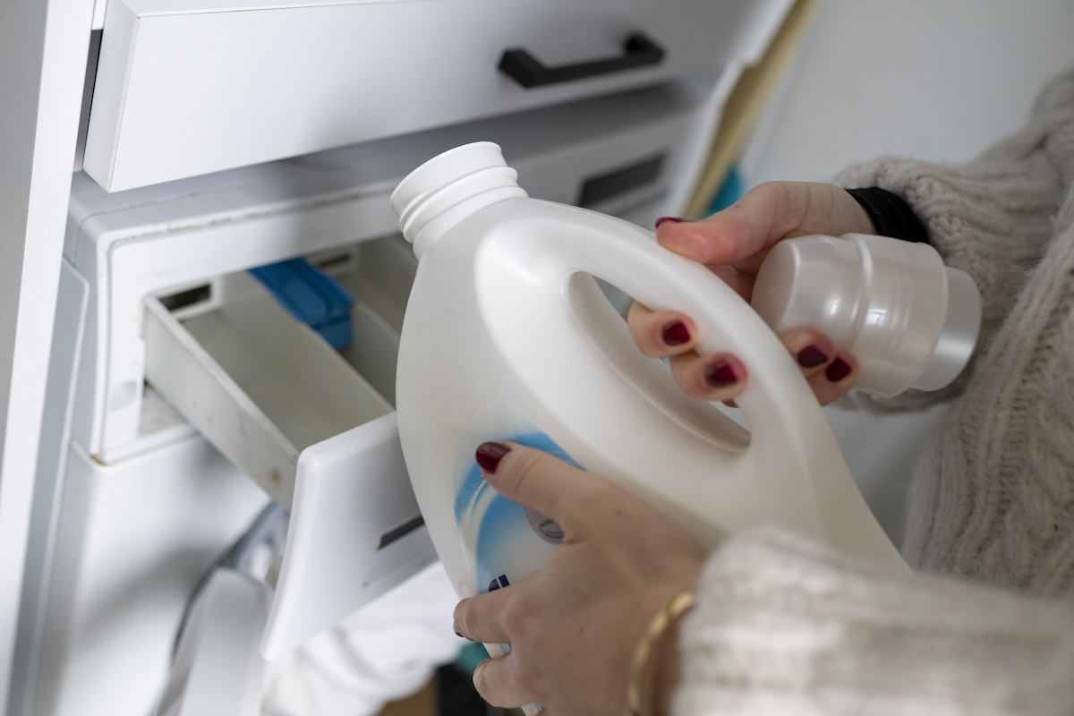 Pouring bleach into a washing machine.