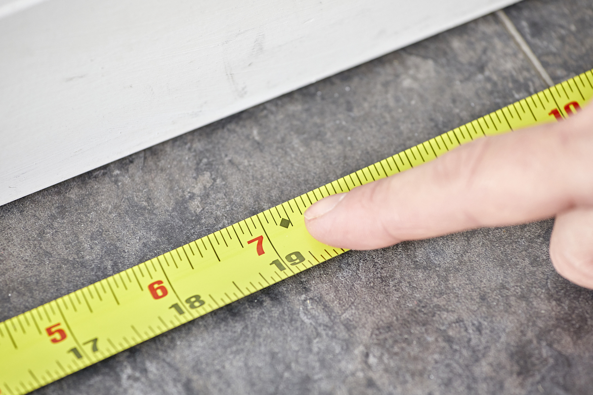 Woman points finger to a black diamond on a tape measure.