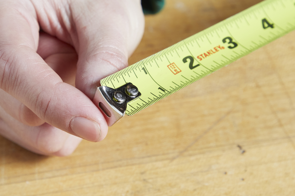 Close up of a woman holding the tang end of a tape measure.