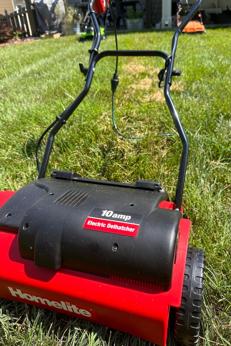 Closeup of a red and black power dethatcher on a lawn.