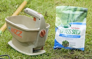 Scotts Grass Seed Sun & Shade Mix next to a hand seed spreader.
