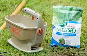 Scotts Grass Seed Sun & Shade Mix next to a hand seed spreader.