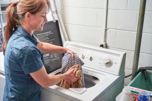 A woman pulls laundry out on a washing machine.