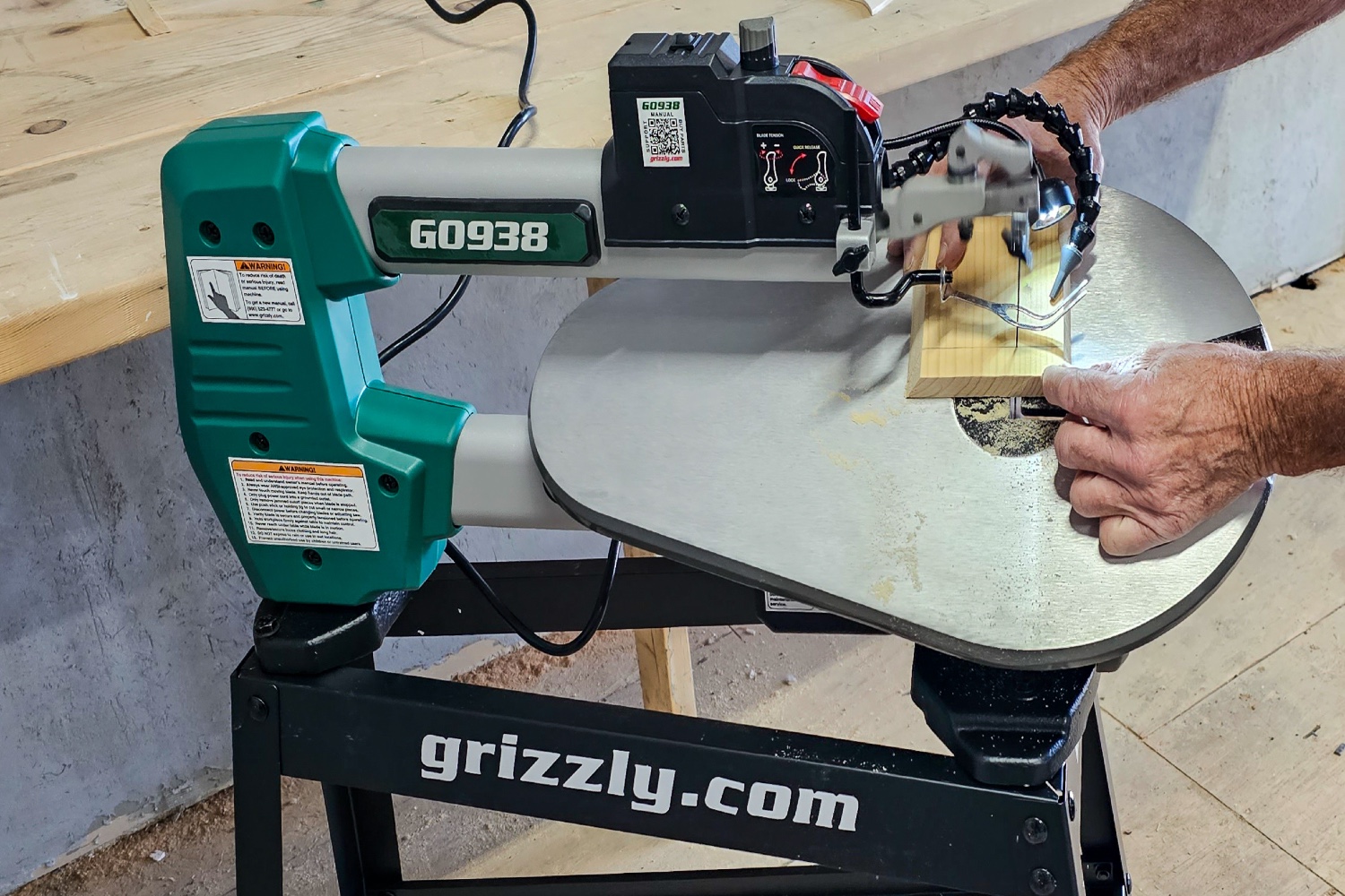 A person using the Grizzly Industrial 18-Inch Scroll Saw With Stand to cut a figure from a piece of wood.