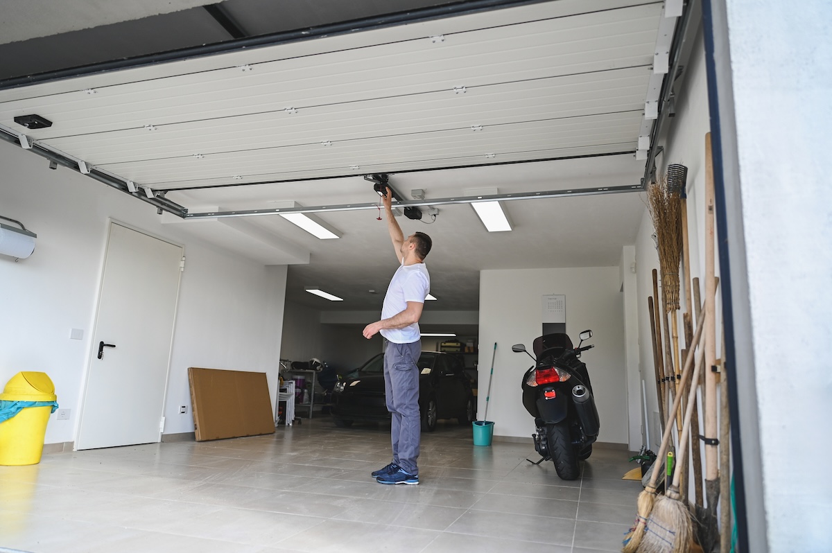 A man works to pull the spring of a garage door.