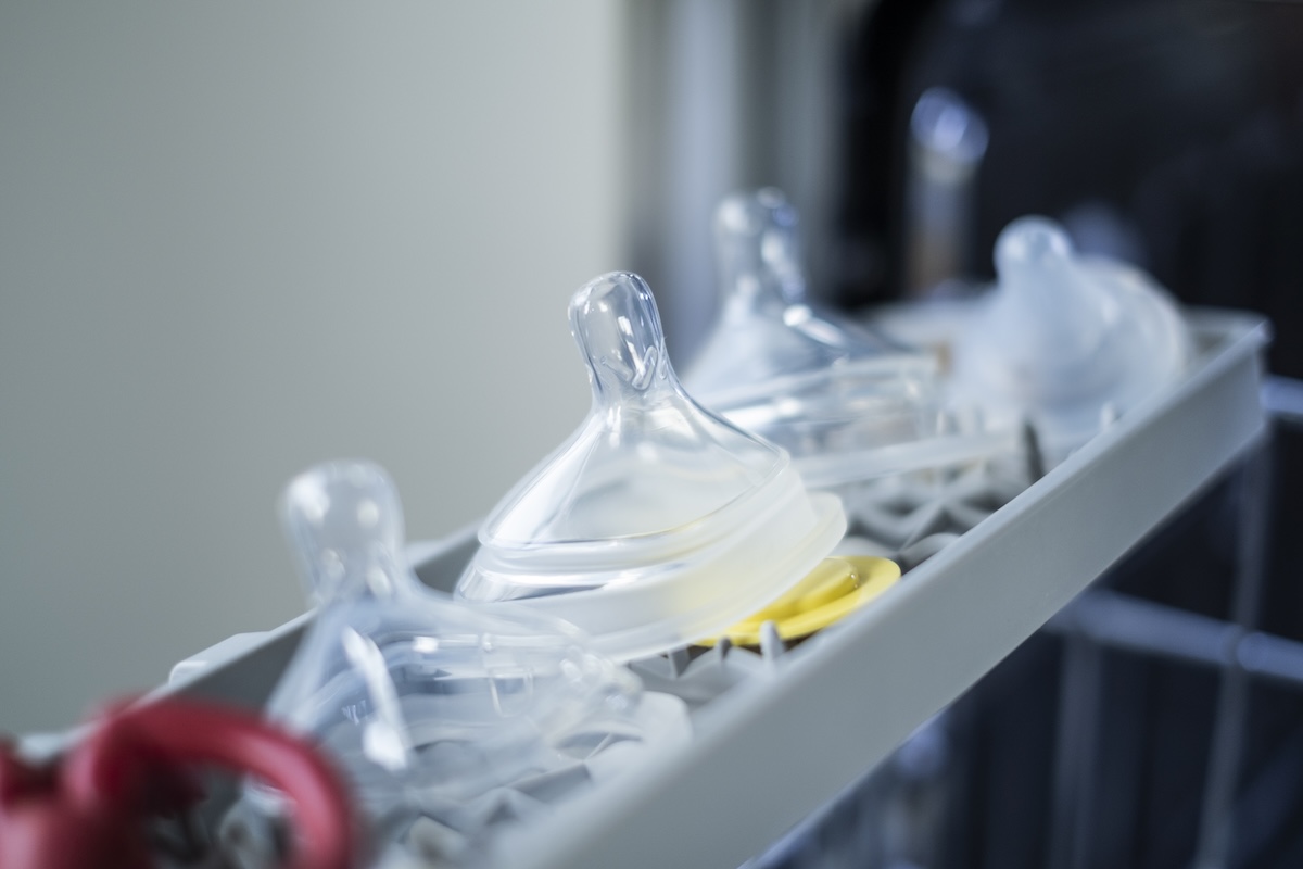 Baby bottle nipples and accessories in dishwasher top rack.