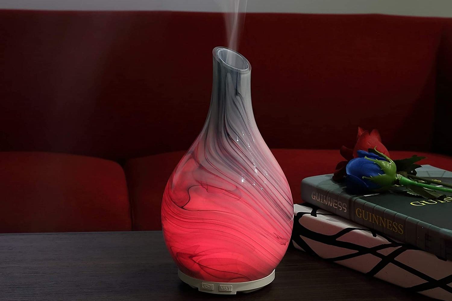 One of the best room humidifiers glowing red and releasing a humidifying mist while on a table.