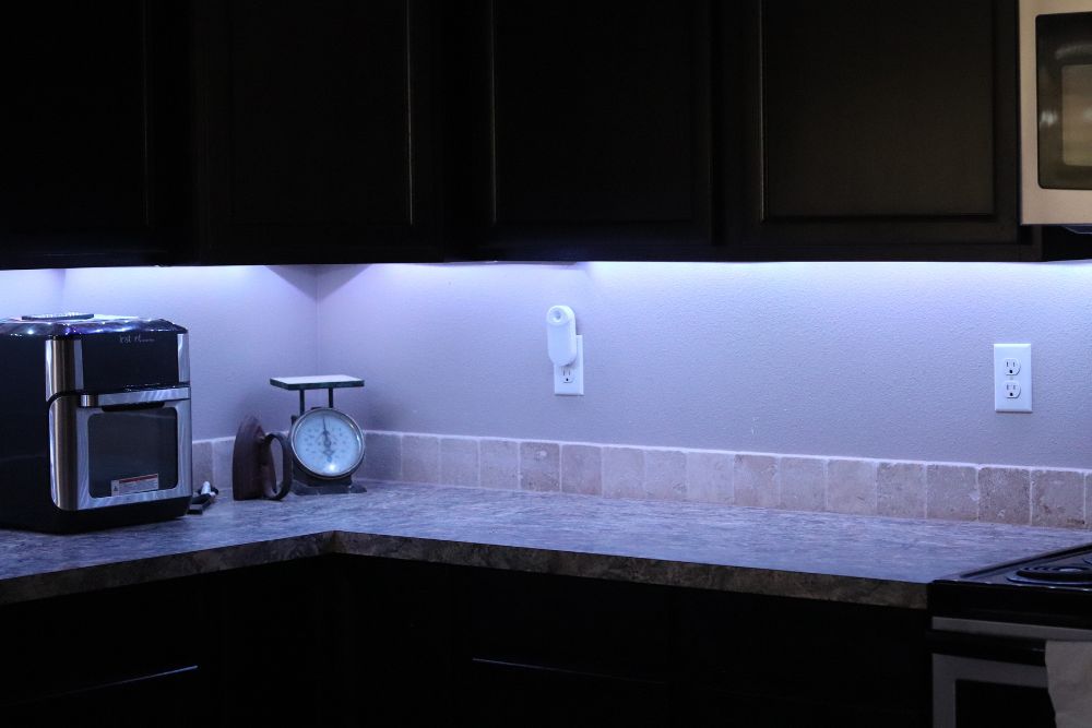The best LED light strips installed under upper kitchen cupboards and providing light for the counters in a dark kitchen.