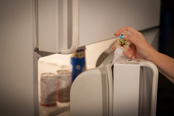 Someone using Gorilla glue to repair a fridge door