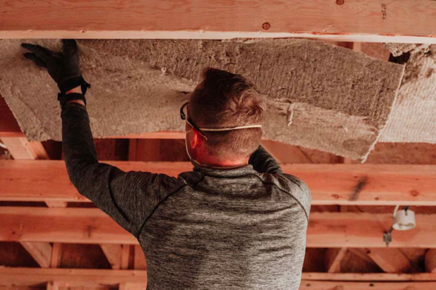 A man hanging sound insulation in a ceiling
