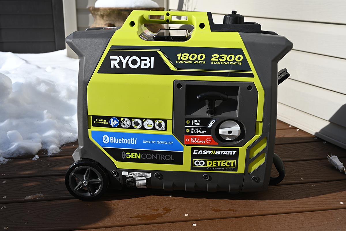Yellow and gray Ryobi inverter generator on deck in front of snow