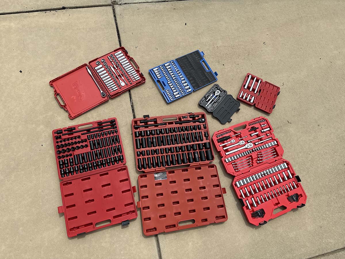 The Best Socket Sets Options laid out in their cases on a cement sidewalk