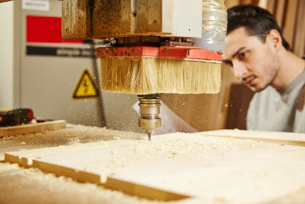 A person looking on as the best router bit dills into a piece of wood.
