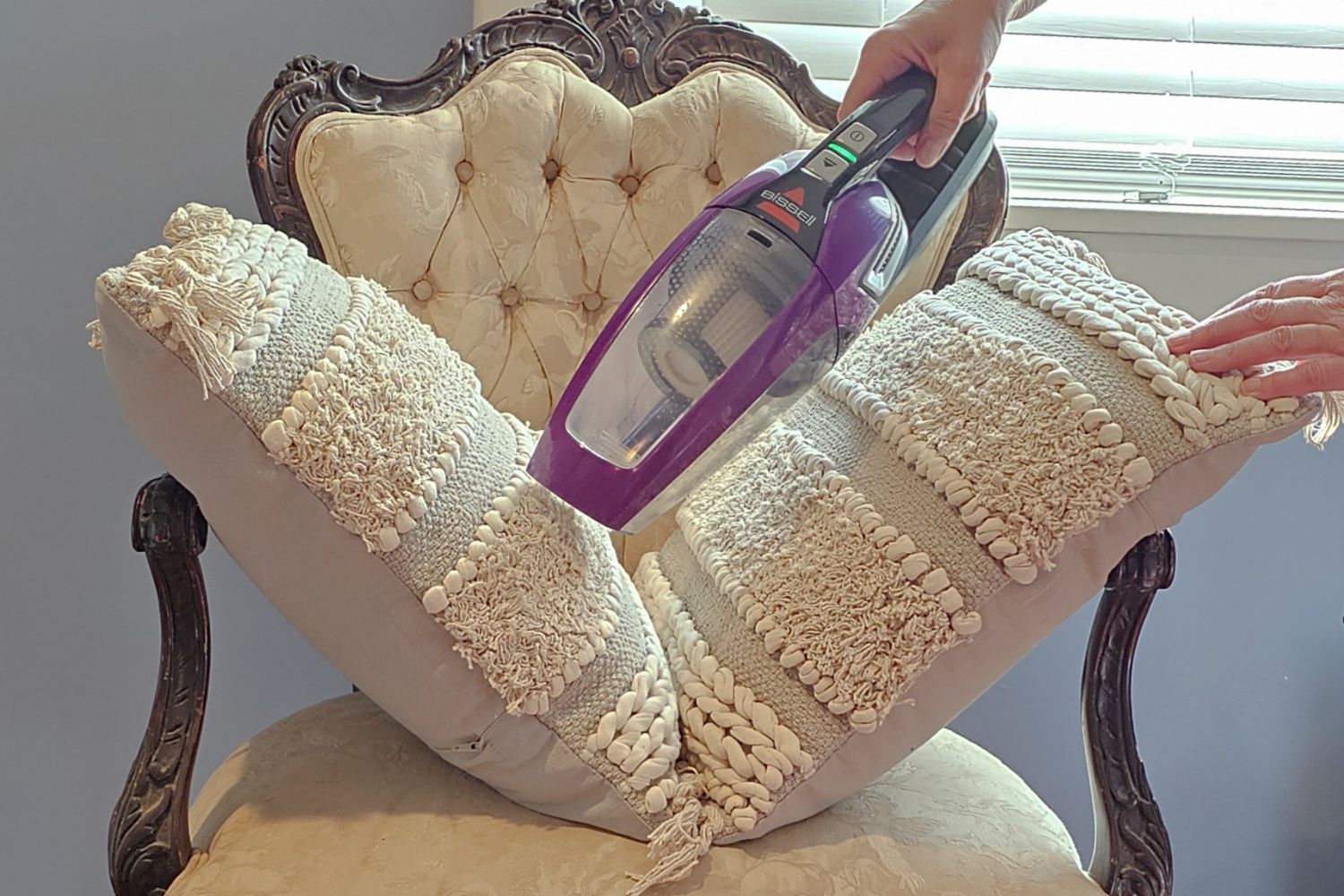 A Hand-Held Version of the Best Cordless Vacuum for Pet Hair, Demonstrating Its Effectiveness on a Chair with Two Pillows