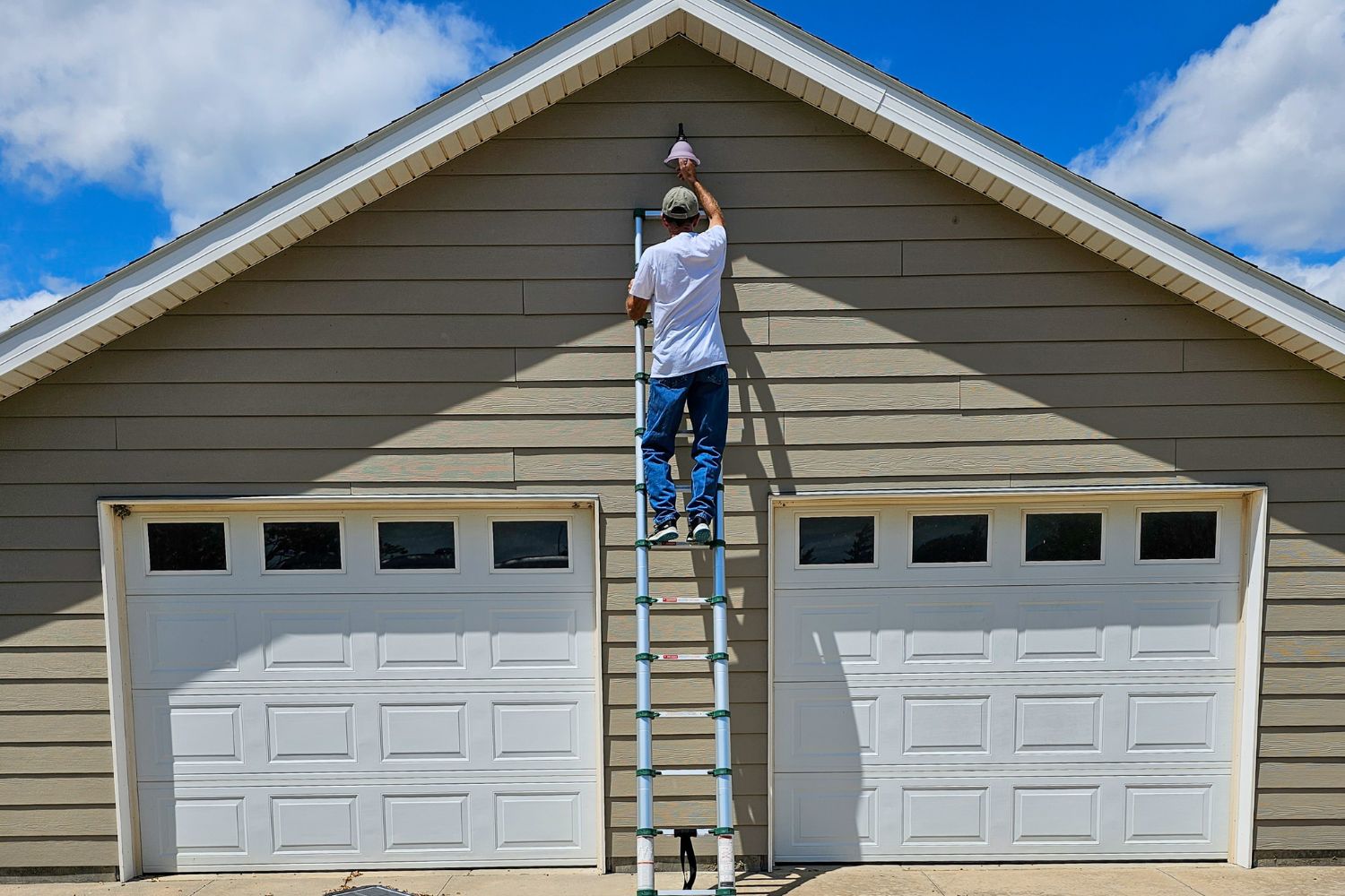A person using the best ladder option to change a light bulb high on a garage