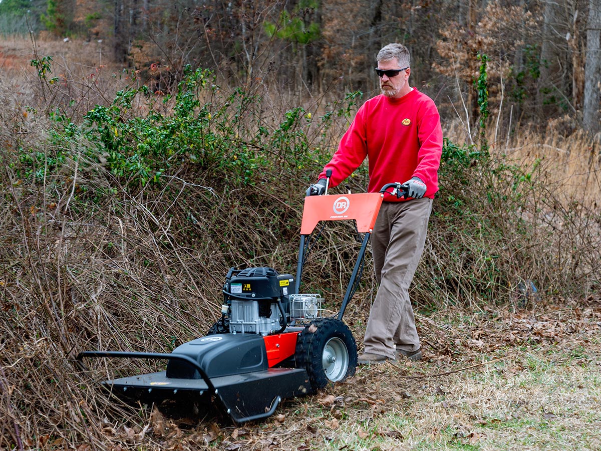 A person using the best walk-behind brush cutter to cut down a large swath of brush. 