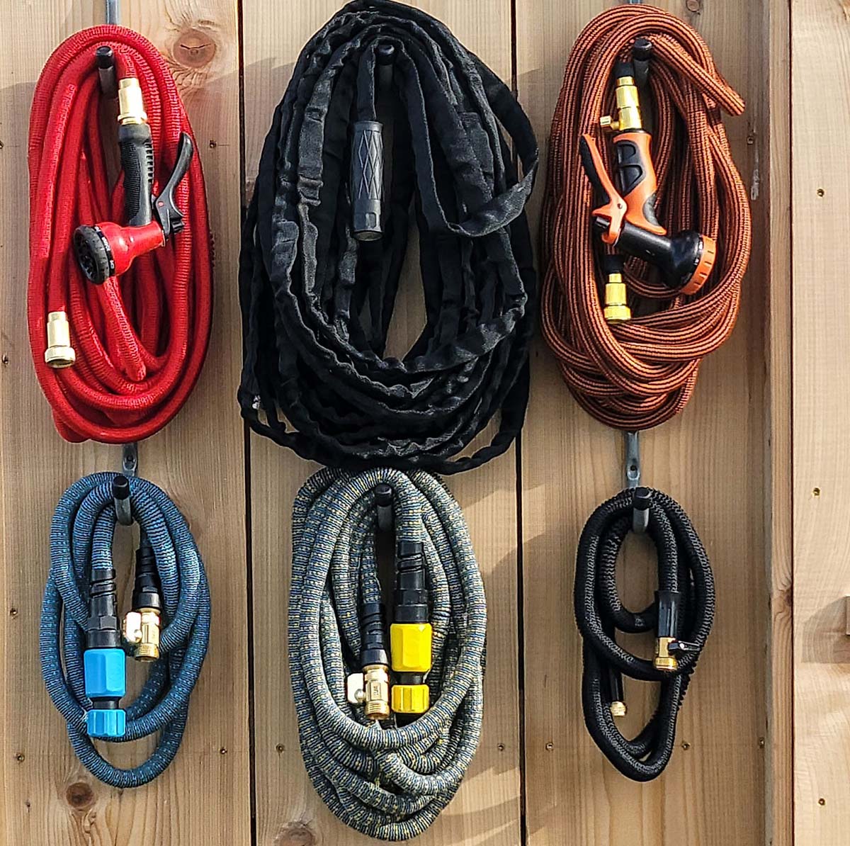 The Best Expandable Hose Options coiled and hanging on a wooden fence