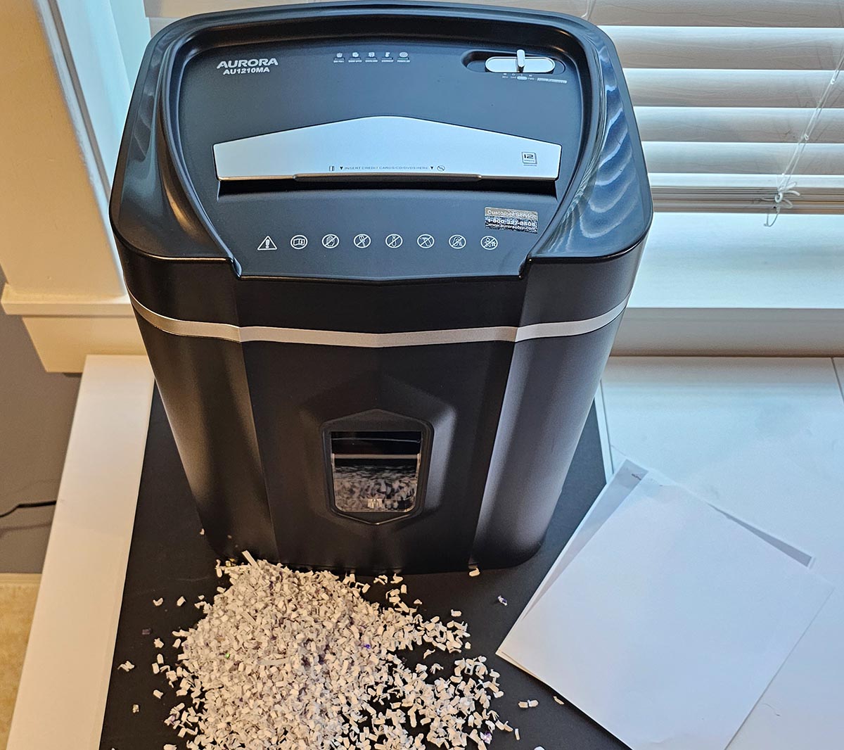 The best paper shredder option next to a stack of paper and a pile of paper that's been shredded