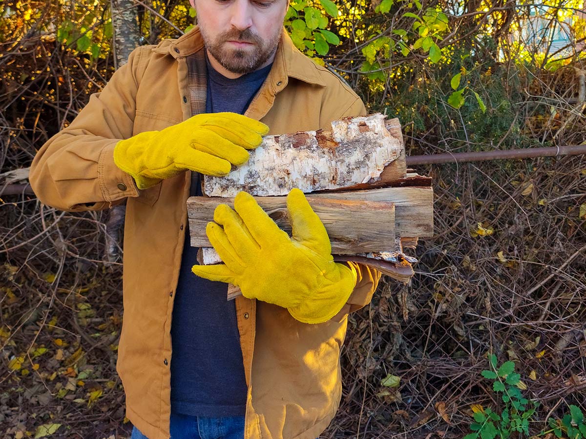 A person wearing the best winter work gloves while collecting firewood outdoors.