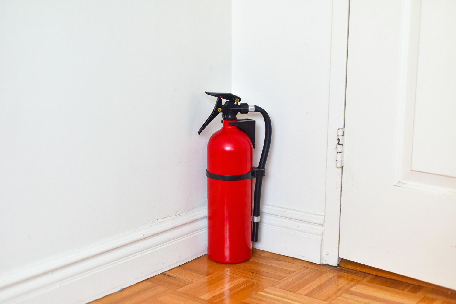 The best fire extinguisher option tucked in a corner on a parquet floor.