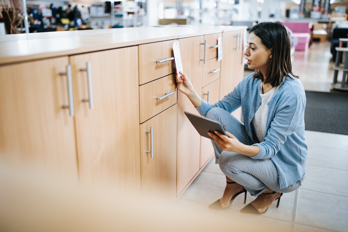A young woman looks at different options of cabinet handles.