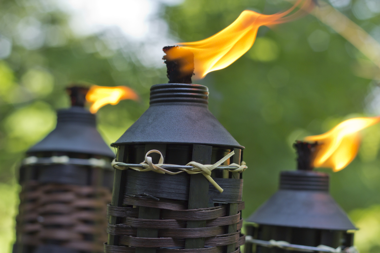 Three lit citronella torches with bamboo bases.