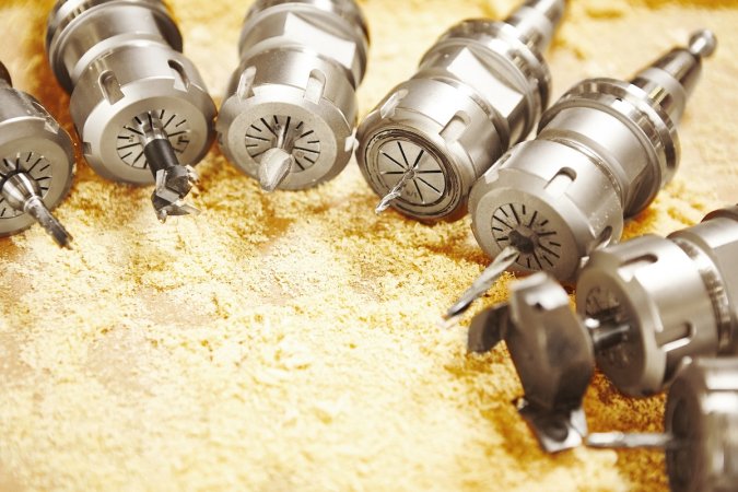 Several router bits lined up in wood shavings.