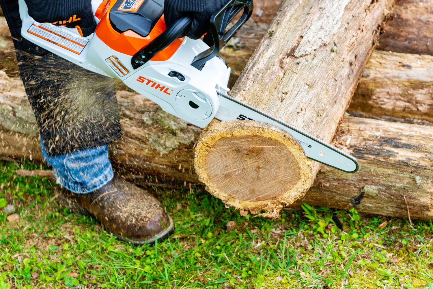 A person using the best battery chainsaw option to cut the end off a felled tree
