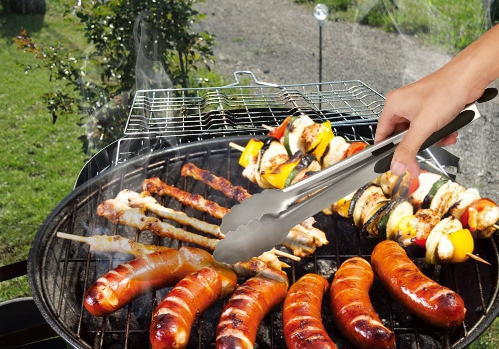 A person using the best grill tongs to move grilling food around on a charcoal grill.