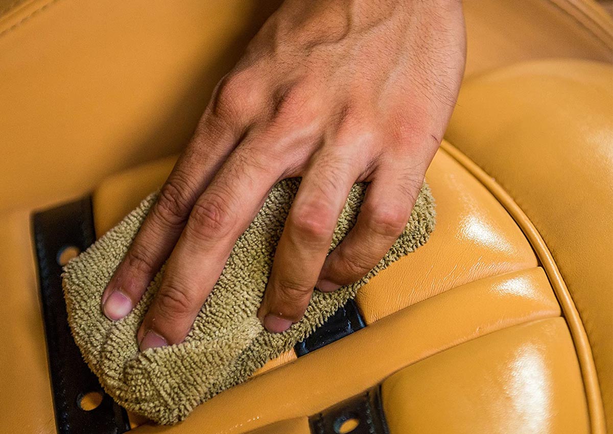 A person wiping a car's leather interior with the best leather cleaner option