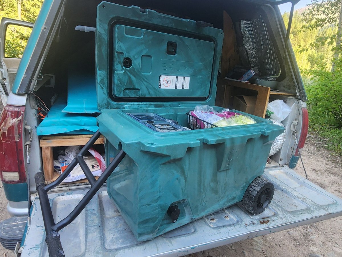 Wheeled teal Brumate cooler in the back of a truck in the woods