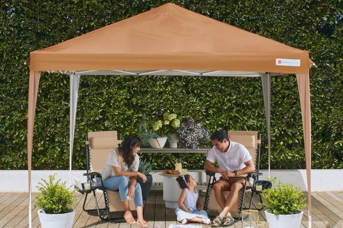 Two adults and a child sitting under a canopy against a leafy background