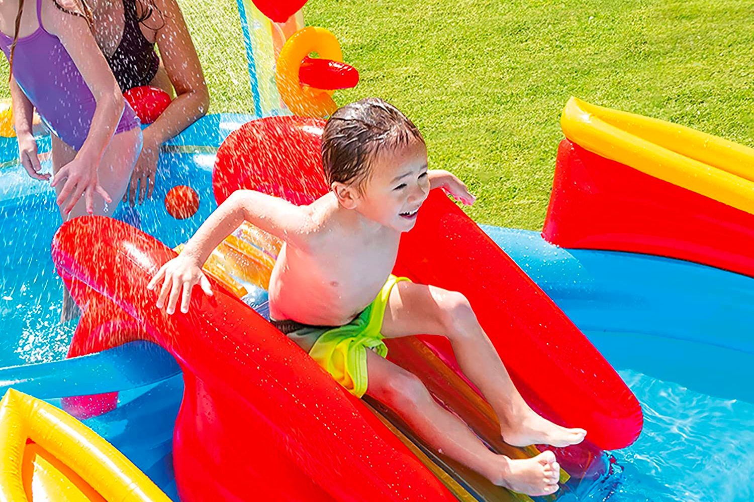A young boy going down a slide on the best above-ground pool option