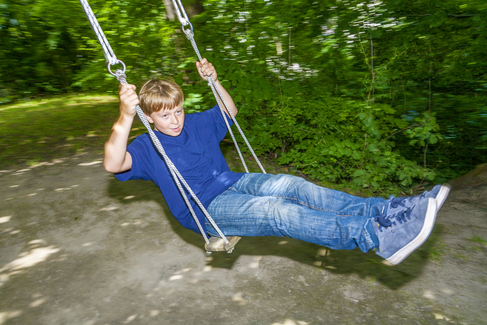 A young boy swinging on the best tree swing option