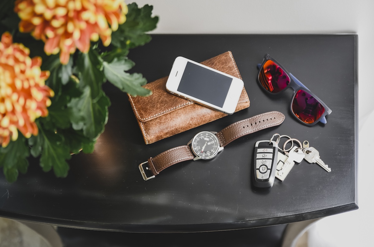 Car keys sit next to a wallet, phone, and watch on a nightstand.