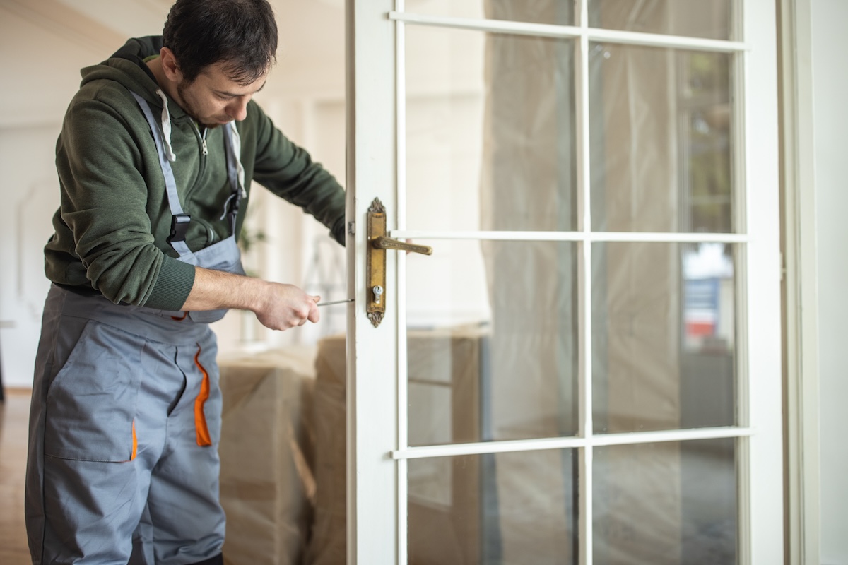 A locksmith updates the locks on a glass door.
