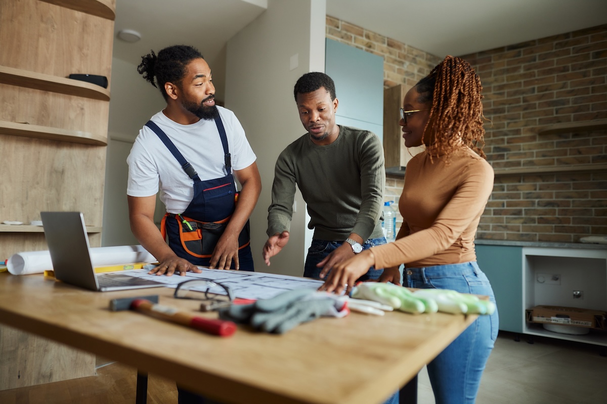 A young couple discusses building plans with a contractor.